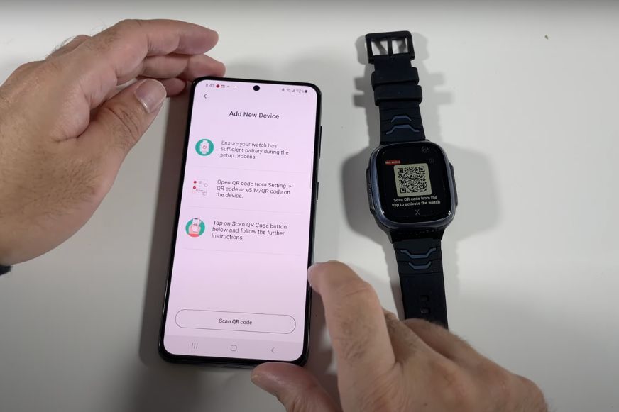 Man sieht die XPLORA X5 Play neben einem Handy auf dem Tisch liegen.